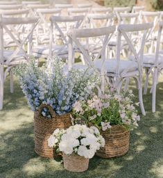 two baskets filled with flowers sitting next to each other on top of a grass covered field