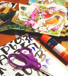 a pair of purple scissors sitting on top of a table next to magazines and markers