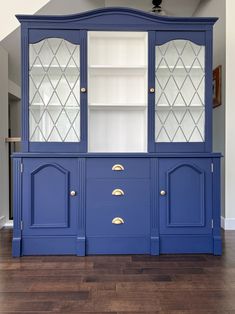 a blue china cabinet with glass doors and gold pulls on the bottom, in a living room