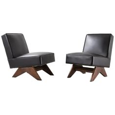 a pair of black leather chairs with wooden legs