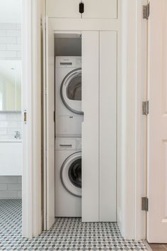 a washer and dryer in a small room with tile flooring on the walls