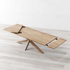 a wooden table sitting on top of a hard wood floor next to a white wall