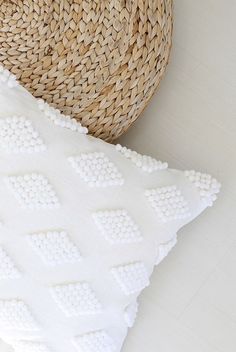 a white pillow sitting on top of a wooden floor next to a woven straw basket