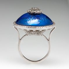 This regal white gold cocktail ring features an engraved yellow gold dome design, topped with blue enamel. The center of the dome is prong set with a cluster of nine (9) round brilliant cut diamonds. The dome is surrounded by a halo, scallop set with sixty (60) round brilliant cut diamonds. The ring measures 24.3mm at the top, rises 15.8mm above the finger, tapering to 2.6mm wide and 1.3mm thick at the base of the shank. It currently fits a size 6. Antique Engagement Rings Sapphire, Estate Jewelry Rings, Wedding Ring Diamond Band, Gold Cocktail Ring, Dome Ring, Gold Cocktail, Antique Engagement Rings, European Cut Diamonds, Domed Ring