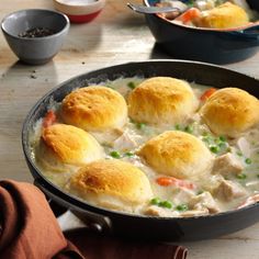 a pan filled with chicken biscuit stew on top of a wooden table