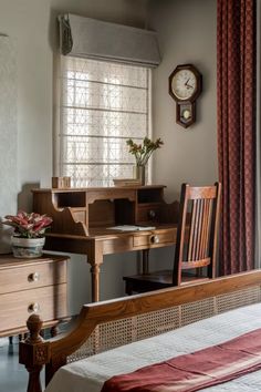 a bedroom with a bed, desk and chair in it next to a clock on the wall