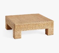 a wicker coffee table with one foot in the middle and two legs on each side