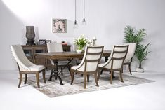 a dining room table with white chairs and a rug on the floor in front of it