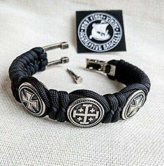 a black bracelet with two silver crosses on it and a badge for the knights in england