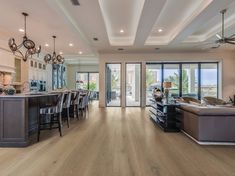 a large open living room and kitchen area with hardwood floors, white walls and ceiling