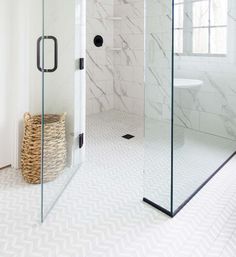 a walk in shower sitting next to a white tiled wall and floor covered in black hardware