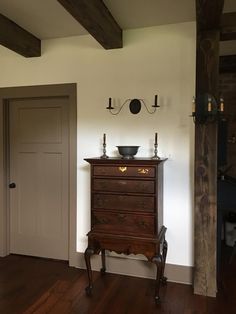 an antique dresser in the corner of a room with wood floors and beams on the ceiling