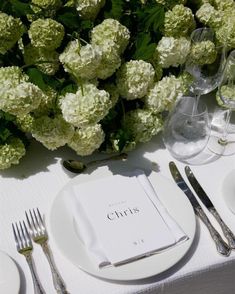 the table is set with white flowers and silverware