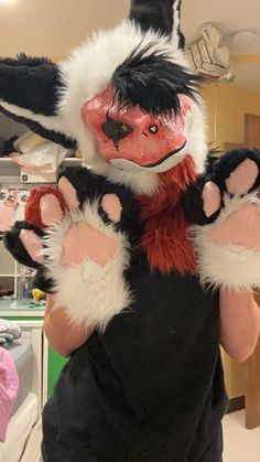 a person wearing a costume with furry ears and claws on their arms, standing in a room