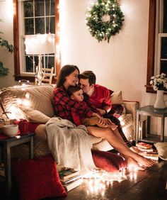 a man and woman sitting on a couch with christmas lights