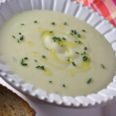 a white bowl filled with soup next to a slice of bread