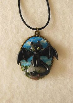 a necklace with an image of a bat hanging from it's side on a black cord