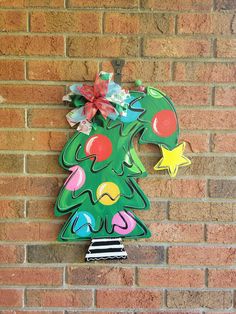 Grab the crooked Christmas tree to add to you holiday decorations! What you will receive in your order: - 1 wood door hanger cut with my jigsaw and painted with a hand tied bow attached if you choose. *Ribbon design may vary depending on stock but will match the door hanger. - 3 felt circle pads for you to stick to the back of your door hanger where it touches your door.   About your item: - This door hanger is cut from ¼" BC Exterior Plywood. - Sanded, hand painted and sealed on both sides with Elf Door Hanger, Porch Sign Christmas, Christmas Tree Door Hanger, Tree Door Hanger, Winter Door Hanger, Christmas Tree Door, Door Decor Christmas, Tree Door, Door Hanger Christmas