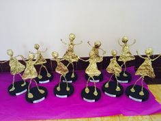 several small gold figurines on black bases with purple cloth in front of them