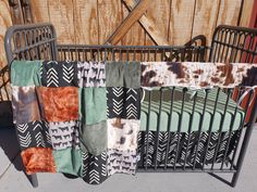 a baby crib with several blankets hanging from it's sides, in front of a wooden fence