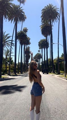 a woman is sitting on a bench in front of palm trees and talking on her cell phone