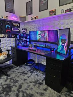 a computer desk with two monitors and a cat sitting on the chair in front of it