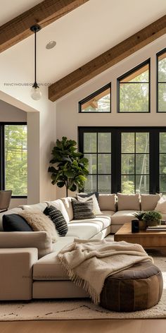 a living room filled with lots of furniture next to large windows and wooden beams on the ceiling