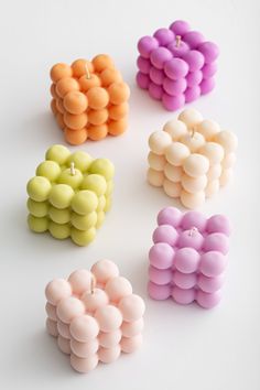 four different colored candles are arranged in the shape of hearts on a white table top