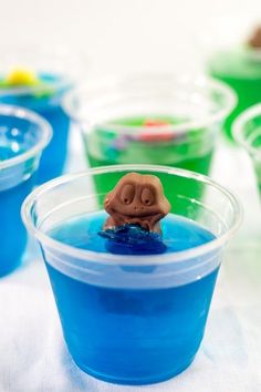 there are many cups with blue and green liquid in them, one has a toy elephant on top