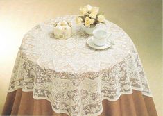 a table topped with a white vase filled with flowers next to a cup and saucer