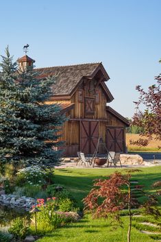 a large wooden barn sitting on top of a lush green field