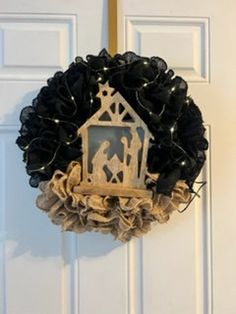 a wreath with a nativity scene hanging from it's side on a door