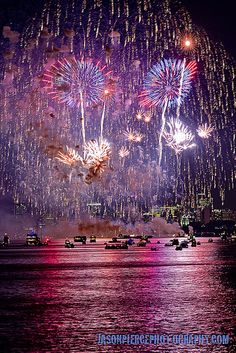 fireworks are lit up in the night sky over water