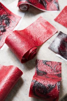 several pieces of red paper with black and white designs on them sitting on a table