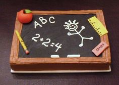 a cake with writing on it that has an apple and pencil in front of it