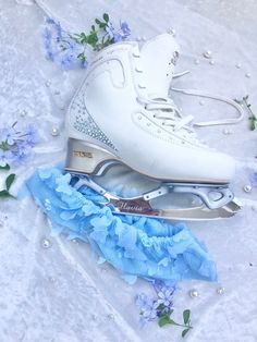 two pairs of ice skates with blue flowers on the ground next to each other