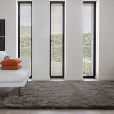 a living room with white furniture and large windows covered in shades of grey blinds on the wall