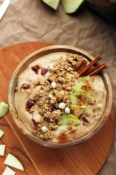 a wooden bowl filled with oatmeal and apple slices on top of a table