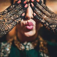 a woman holding her hands over her face with hendi tattoos on it's arms