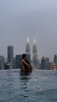 a woman sitting in the middle of a swimming pool with cityscape in the background