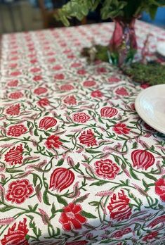 the table cloth is red and green with flowers on it, along with a white plate