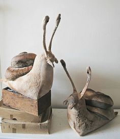 two antelope sculptures sitting next to each other on top of a shelf in front of a white wall