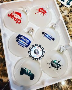 six glass ornaments in a tray on a marble counter top with stickers and magnets