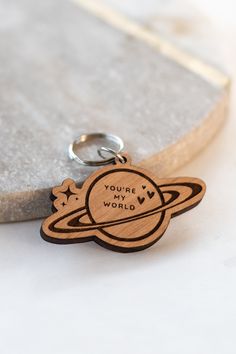 a wooden keychain with the words you're my world on it