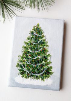 a painting of a christmas tree on a white surface next to pine cones and needles