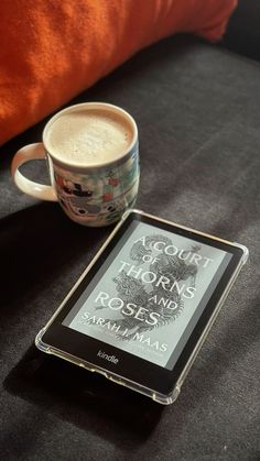 a coffee cup sitting on top of a table next to a tablet