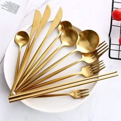 a white plate topped with gold colored spoons and forks