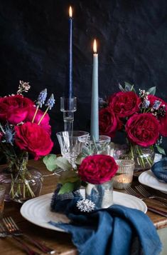 the table is set with candles, plates and flowers in vases on top of it