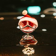 a mercedes car with a christmas hat on it's hood is reflected in the shiny surface