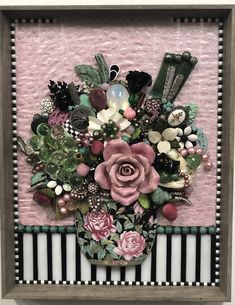 a pink and black flower arrangement in a wooden frame on a wall with white stripes